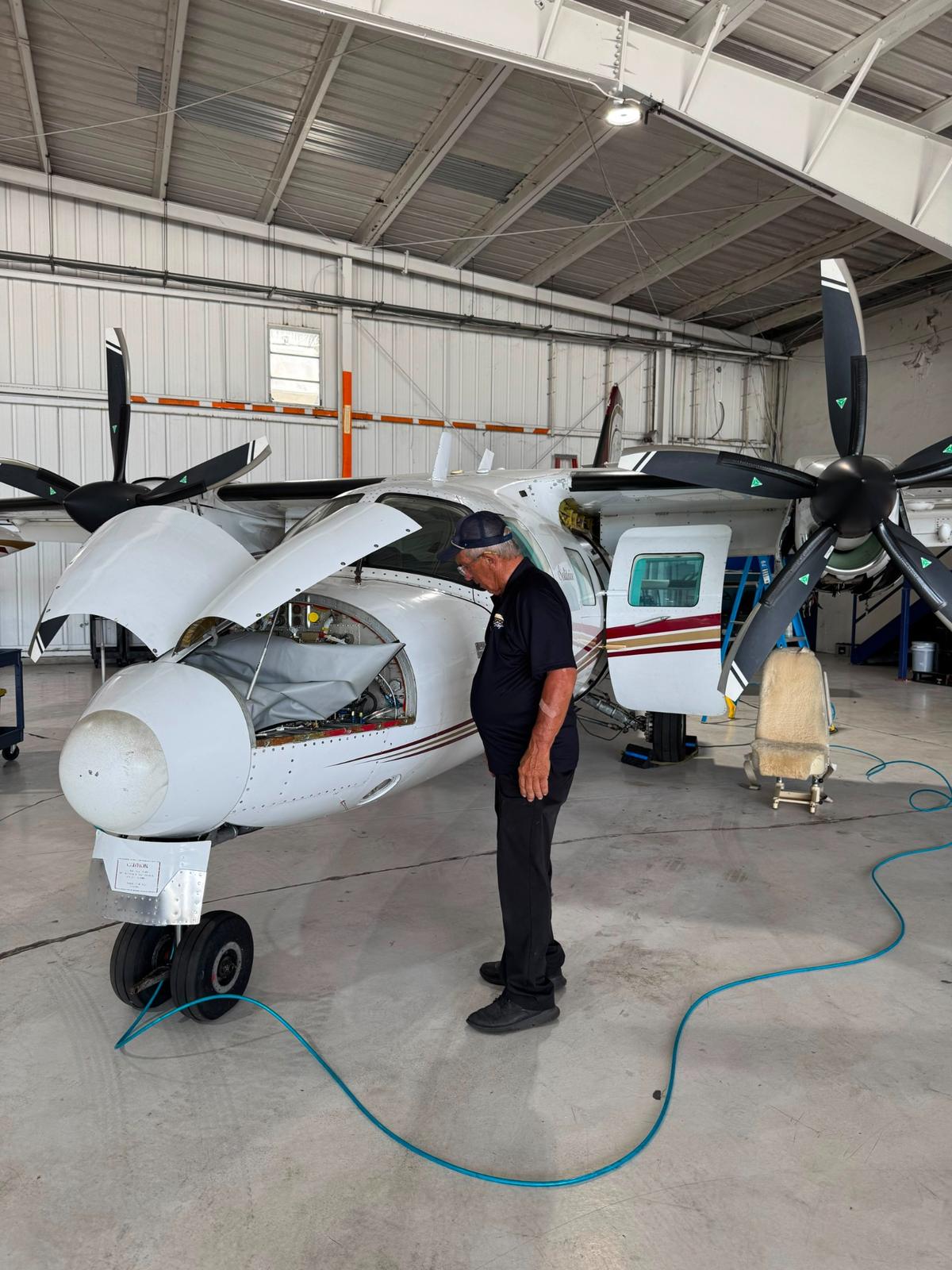 305 Sky technician inspecting the open engine nacelle of a twin-engine Commander.