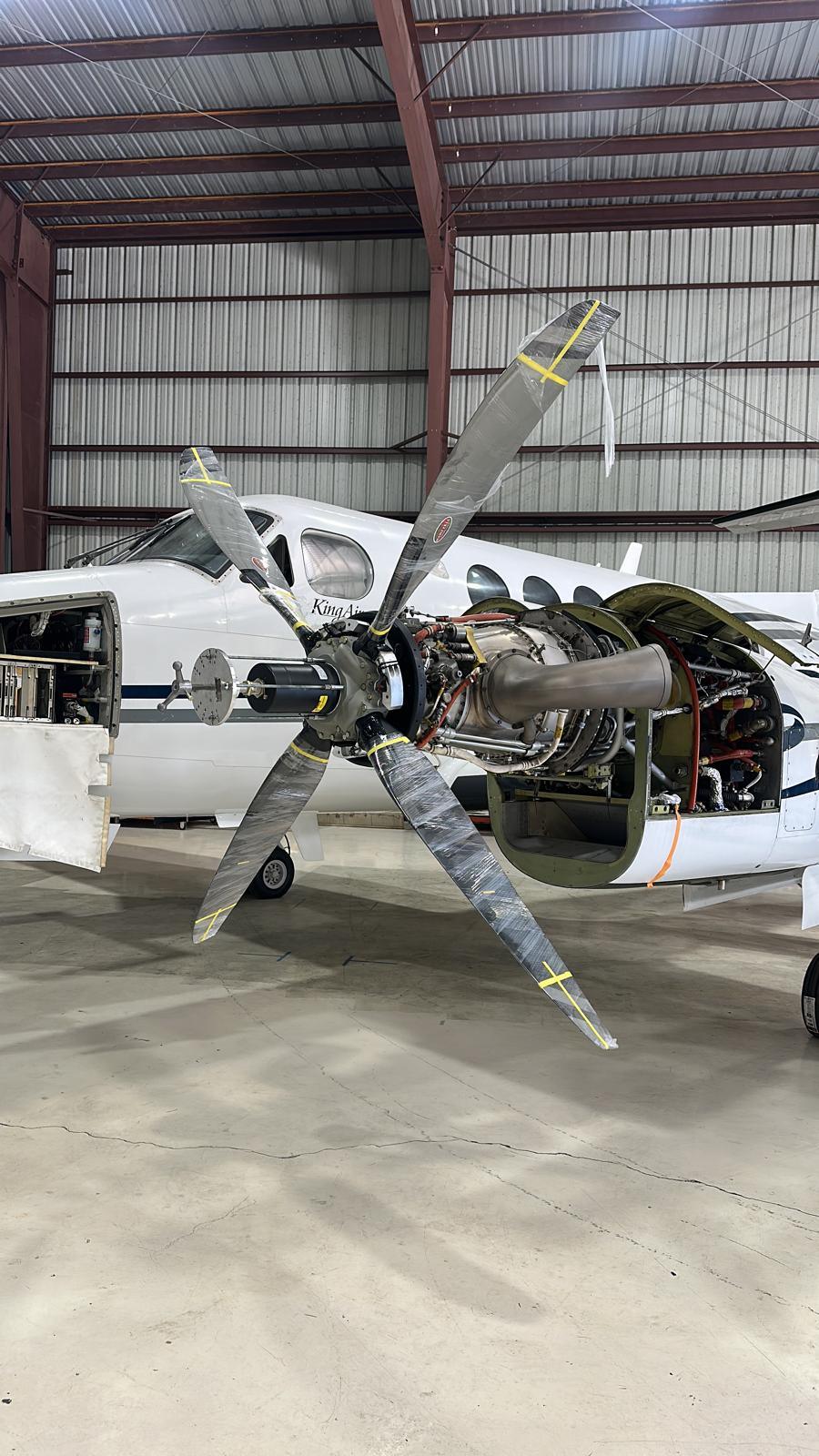 King Air with propeller blades wrapped and taped while the engine sits fully exposed.