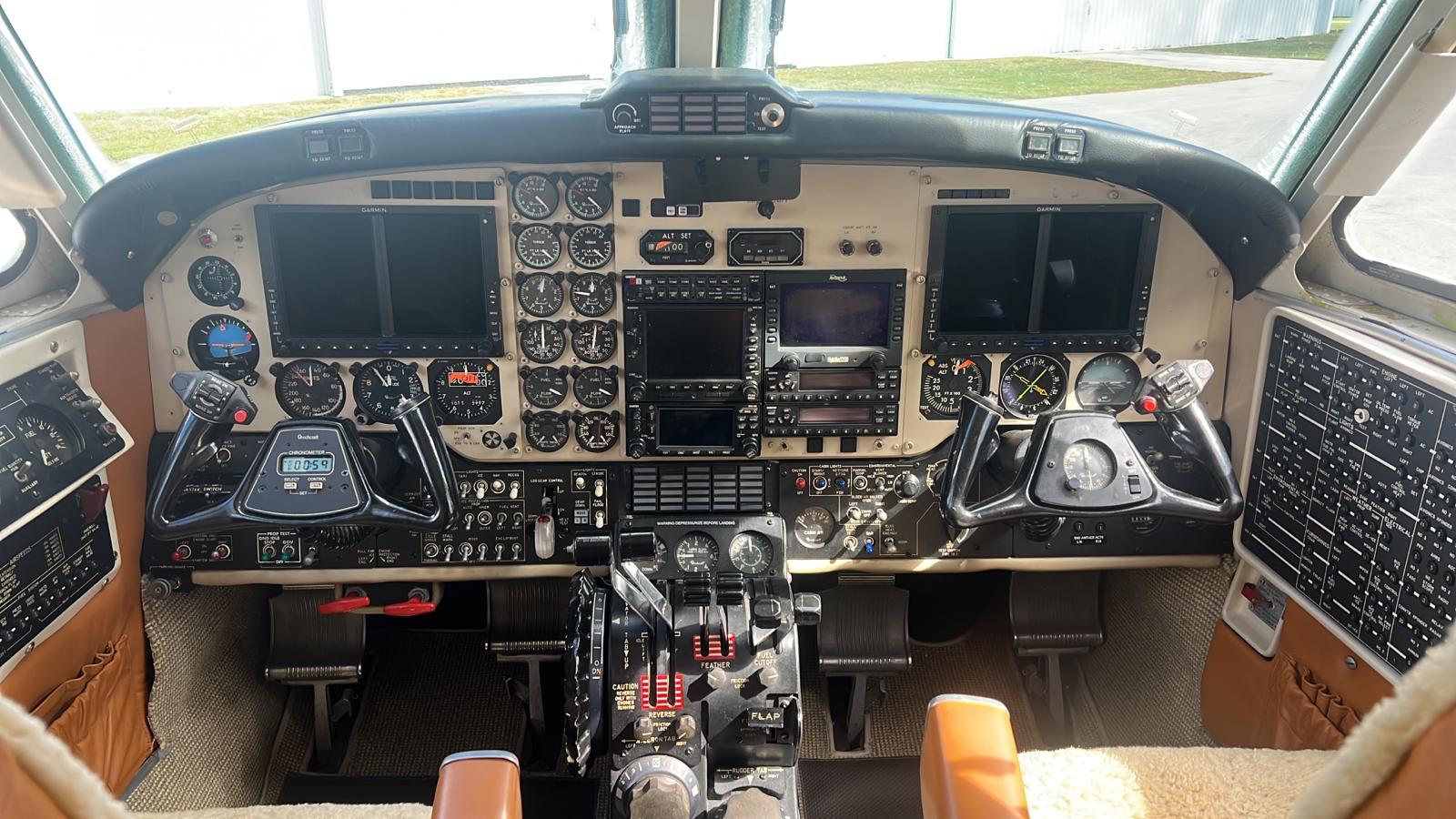 King Air C90B panel with Collins radios, Garmin navigator and annunciator lights illuminated.