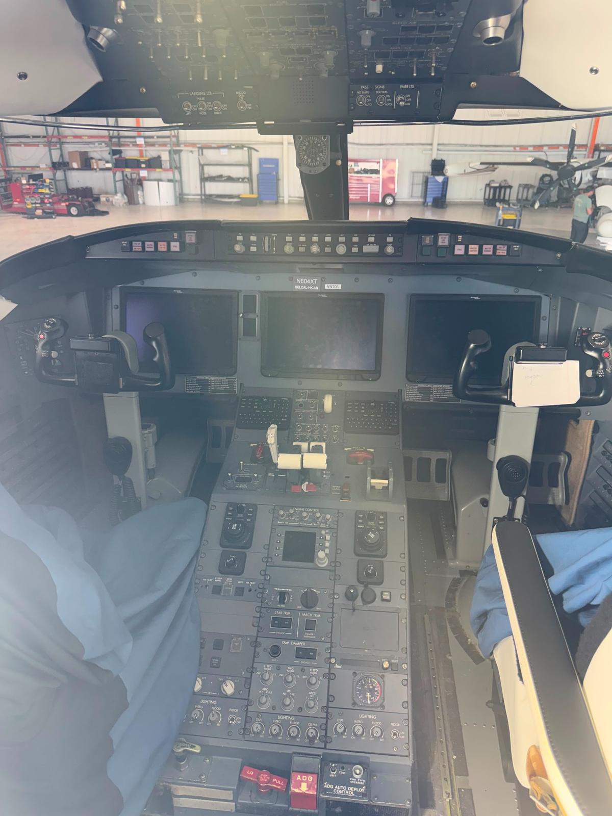 Bombardier Challenger cockpit with three large multifunction displays and overhead panel.