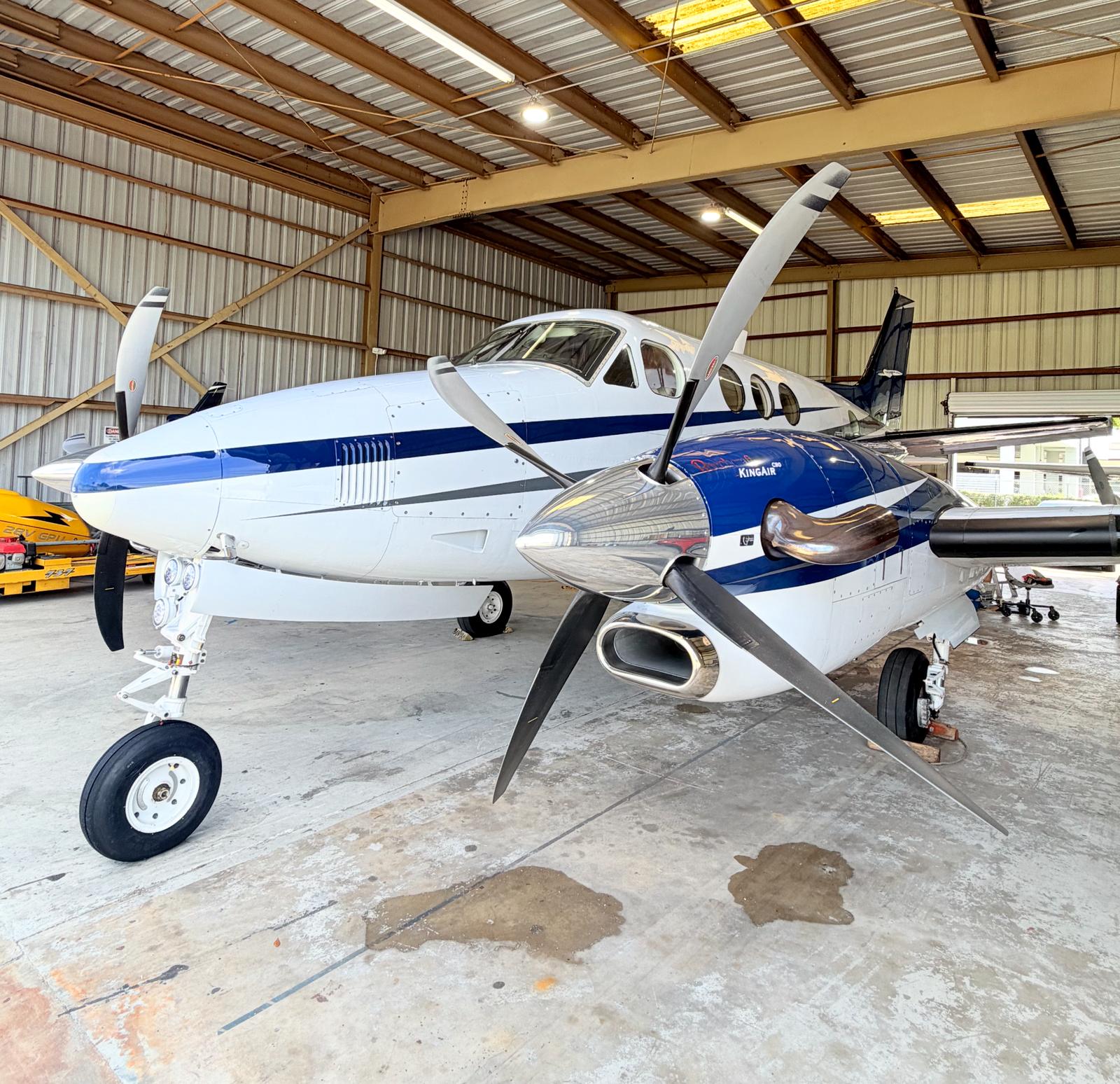 Blue-and-white King Air photographed in the hangar after exterior work.