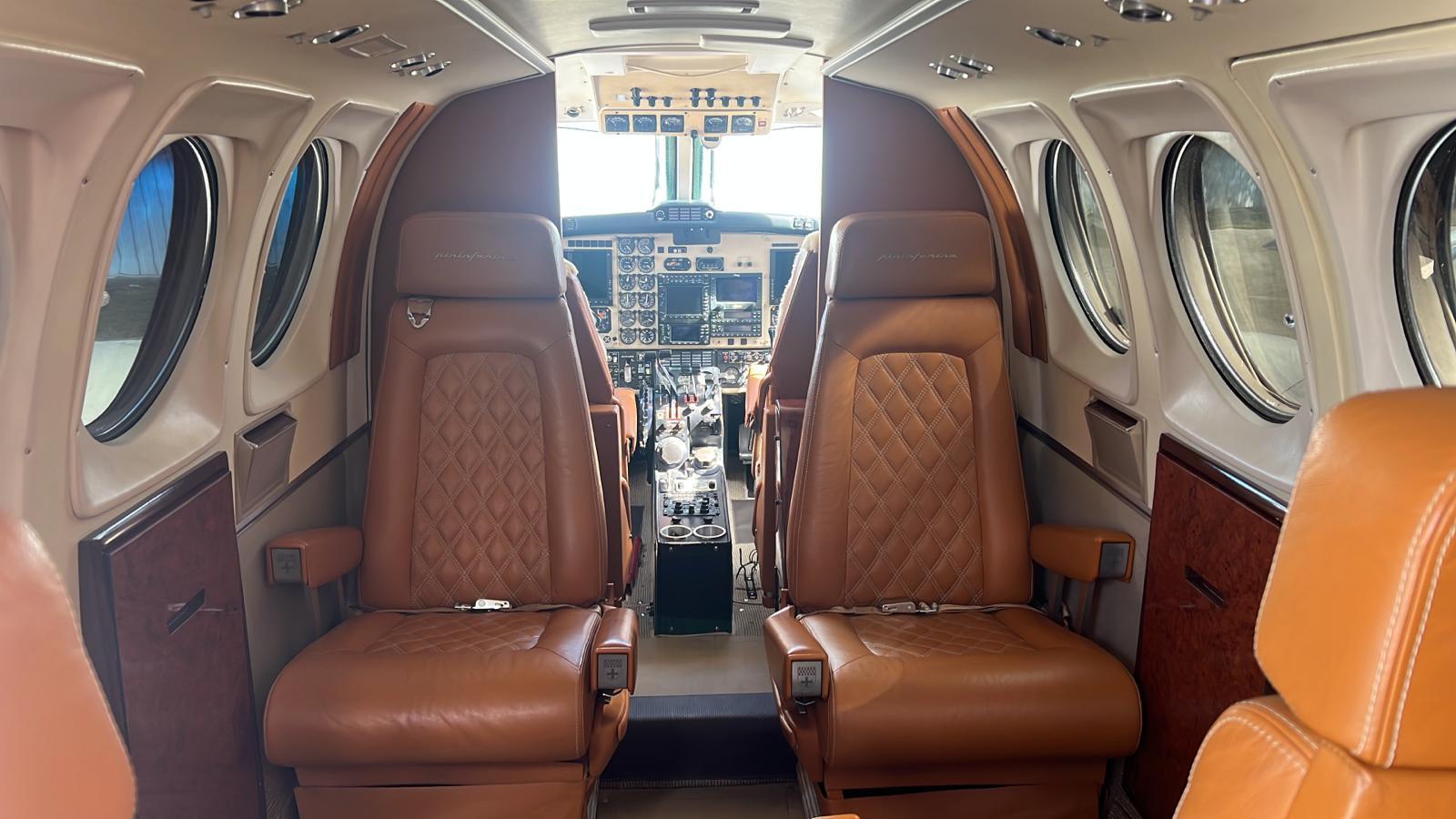 King Air cabin with cognac leather club seating and burl veneer panels looking forward to the cockpit.
