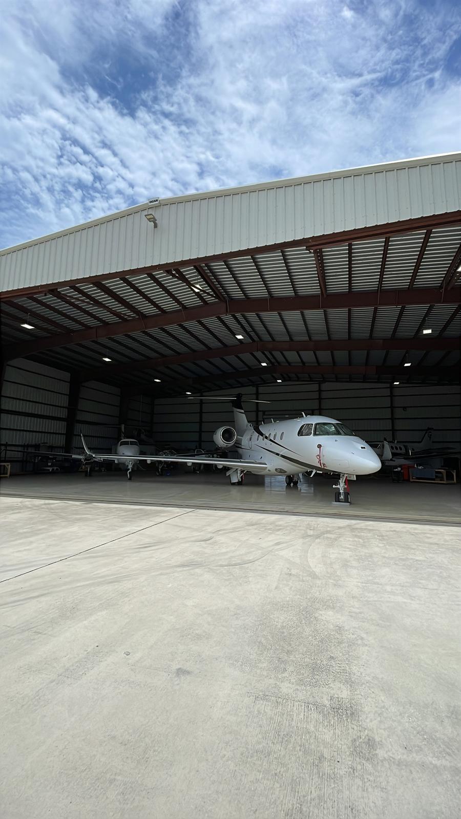 Business jet framed in the open hangar door under a bright Florida sky.