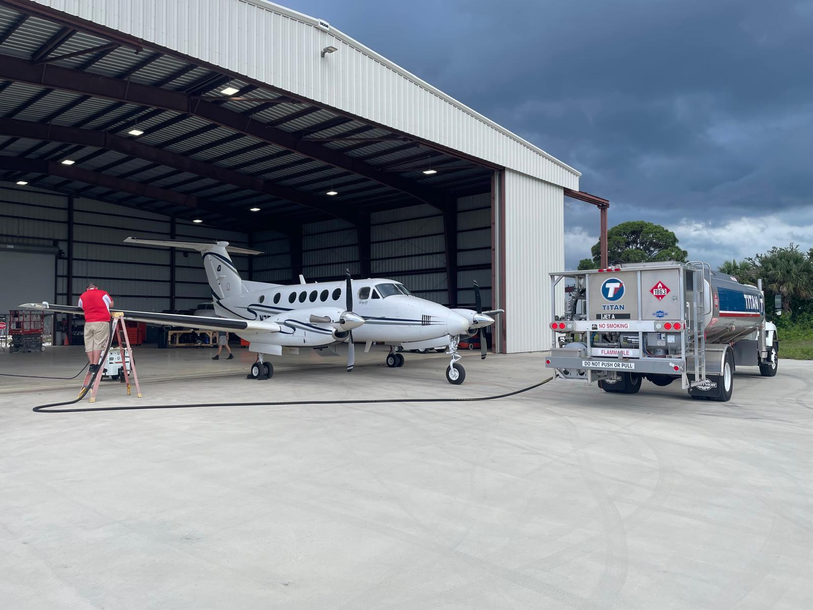 King Air being refuelled from a Jet A truck outside the hangar under a stormy sky.