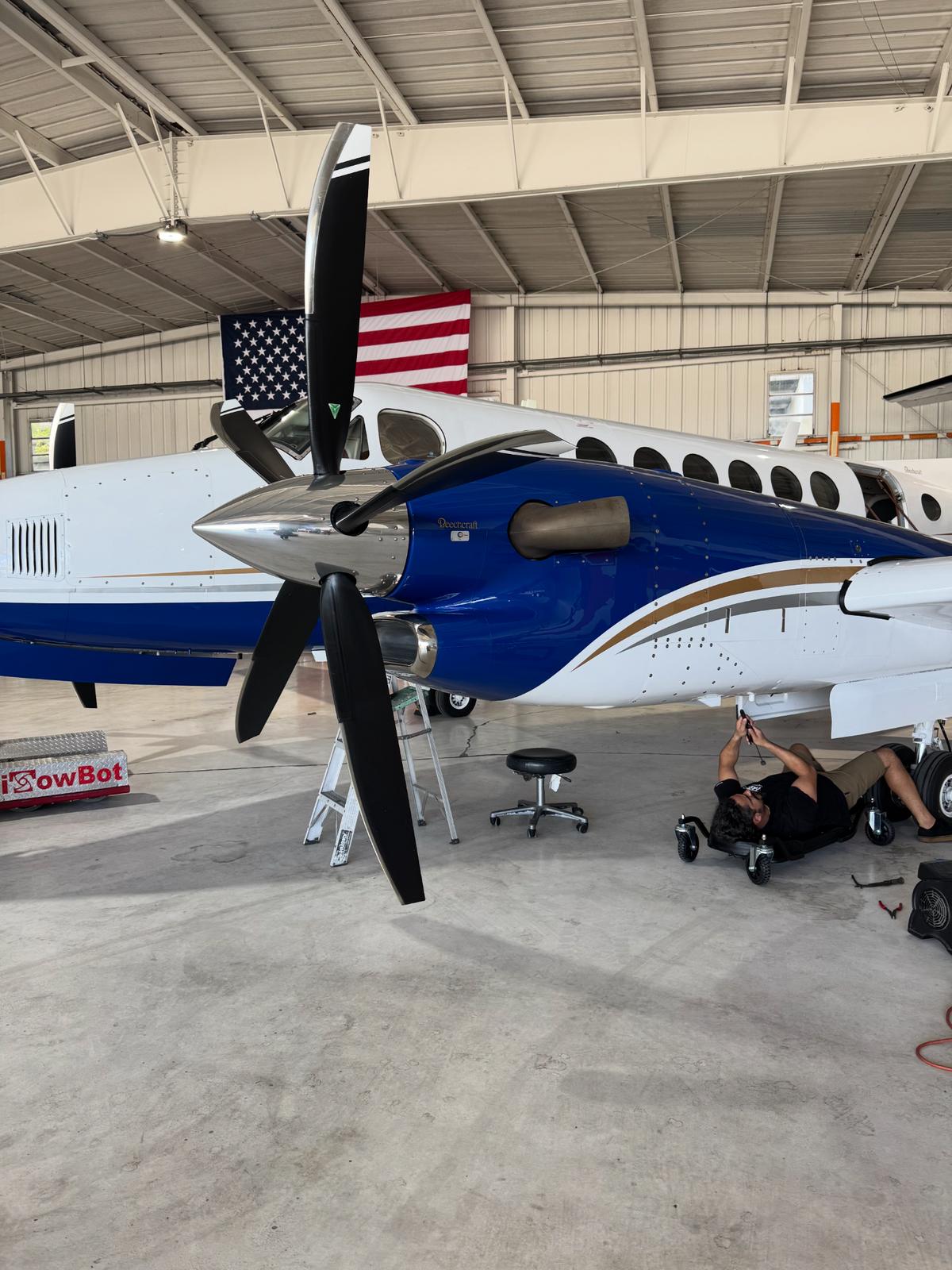 King Air N222PV back in the hangar after its blue-and-white exterior transformation, undergoing ongoing maintenance.
